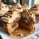 Close-up of a pecan pie cupcakes cut in half, showing the cake, filling, and pecan frosting.