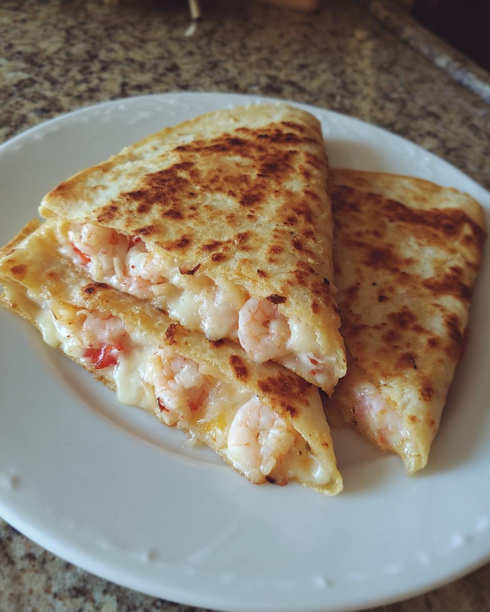 Two golden-brown wedges of shrimp quesadilla cut open to show melted cheese and pink shrimp filling.