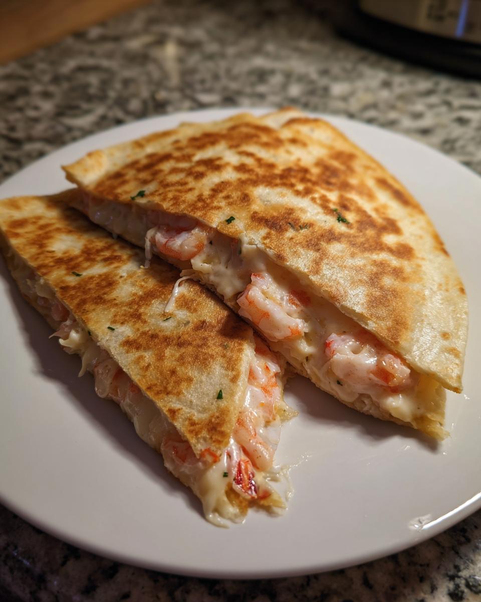 Two halves of a golden-brown shrimp quesadilla, showing melted cheese and pink shrimp filling.