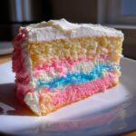 A slice of fluffy cotton candy cake showing pink, blue, and yellow layers with white frosting.