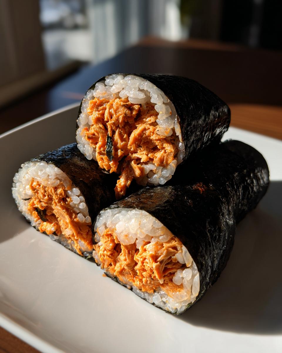 Three thick-cut pieces of tuna kimbap showing a generous, bright orange spicy tuna filling wrapped in seaweed and rice.