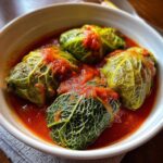 Close-up of four delicious Stuffed Cabbage Rolls served in a white bowl with rich tomato sauce.