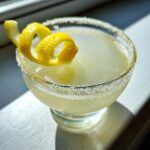 Close-up of a chilled Lemon Drop cocktail in a sugar-rimmed glass, garnished with a bright lemon peel spiral.