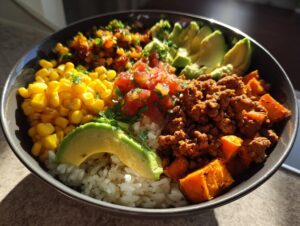 A vibrant sweet potato taco bowl featuring rice, seasoned ground meat, roasted sweet potato chunks, corn, salsa, and sliced avocado.