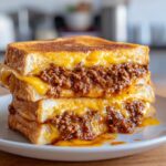 Close-up of stacked texas toast sloppy joes with melted cheddar cheese oozing out.