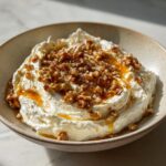 A bowl of creamy whipped ricotta dip topped generously with chopped walnuts and a drizzle of golden honey.