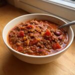 A close-up of a hearty bowl of amazing 1-hour chili, rich with ground meat, tomatoes, and kidney beans.