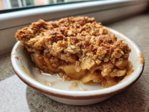 Close-up of a serving of amazing apple crisp showing the bubbly, saucy filling and crunchy oat topping.