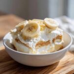 A delicious serving of banana pudding layered with wafers, cream, and topped with fresh banana slices.