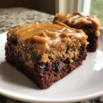 Two squares of rich banana bread brownies topped with a thick layer of gooey caramel frosting.
