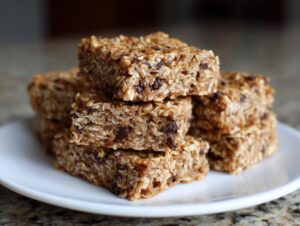 A stack of chewy oatmeal bars loaded with chocolate chips resting on a white plate.