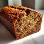 A close-up, cross-section view of a moist chocolate chip best banana bread loaf with a golden-brown crust.