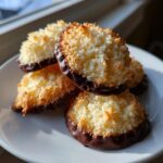 Close-up of delicious, golden-brown italian butter cookies dipped in dark chocolate, stacked on a white plate.