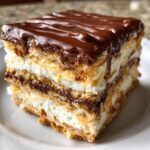 Close-up of a layered slice of chocolate eclair cake with creamy filling and rich chocolate glaze.