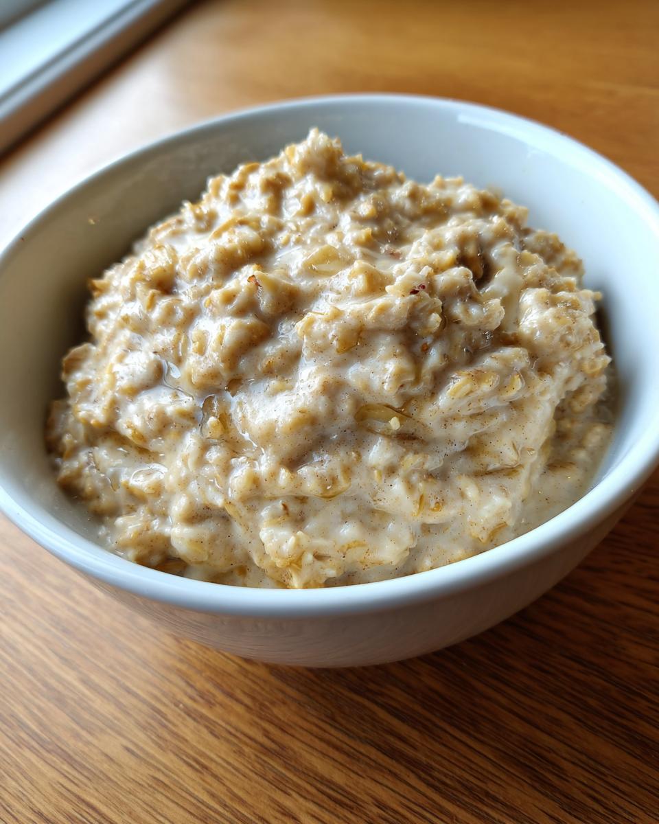Close-up of a bowl of creamy banana oatmeal, showing texture and a drizzle of liquid sweetener.