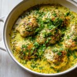 Five pieces of seared coconut lime chicken simmering in a rich, yellow coconut-lime sauce, topped with fresh cilantro.