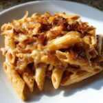 Close-up of creamy french onion pasta made with penne, covered in rich sauce and topped with crispy caramelized onions.
