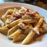 Close-up of creamy Marry Me Chicken Pasta featuring penne, diced chicken, and sun-dried tomatoes.