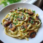 Close-up of creamy mushroom pasta featuring fettuccine noodles, sautéed mushrooms, and fresh parsley garnish.
