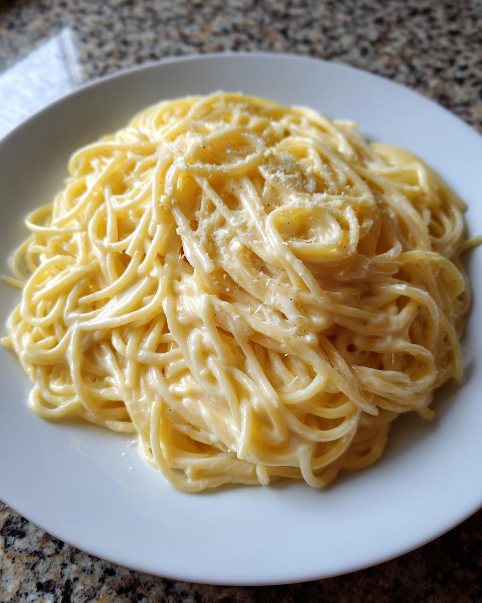 A close-up of creamy spaghetti coated in a rich sauce, ready to eat, showcasing the amazing parmesan pasta.