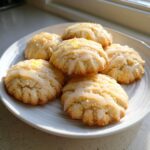 A plate of six freshly baked earl grey cookies drizzled with a light glaze and sprinkled with zest.