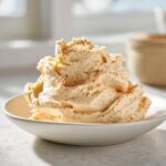 A generous, fluffy mound of homemade cinnamon butter dusted with spice in a small white bowl.