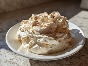 A generous serving of fluffy, homemade cinnamon butter, lightly dusted with ground cinnamon, served on a white plate.