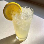 A tall glass filled with ice and homemade lemonade, garnished with a bright lemon slice.