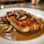Close-up of a breaded and pan-fried chicken marsala cutlet topped with rich brown mushroom sauce.