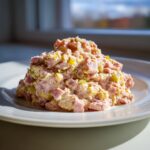 A mound of creamy ham salad recipe featuring diced ham and relish served on a white plate.
