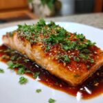 Close-up of a perfectly cooked honey garlic salmon recipe fillet glazed with sauce and topped with fresh parsley.