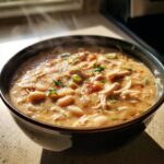 Close-up of a steaming bowl of creamy instant pot white chicken chili, featuring shredded chicken and white beans.