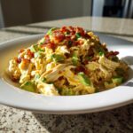 A generous serving of creamy honey mustard chicken salad mixed with chunks of avocado and topped with crispy bacon bits.