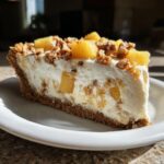 A generous slice of million dollar pie with a thick graham cracker crust, creamy filling, pineapple chunks, and chopped pecans.