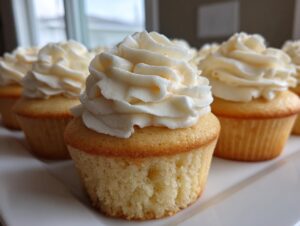 Close-up of several moist vanilla cupcakes topped with perfectly piped white vanilla frosting.