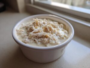 Close-up of shredded chicken submerged in creamy sauce, representing homemade cream of chicken soup.