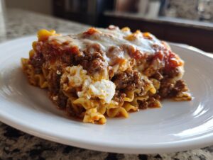 A generous serving of cheesy, meaty skillet lasagna with ruffled noodles on a white plate.