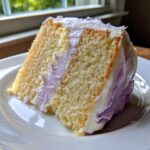 Close-up of a moist slice of yellow lavender cake layered and frosted with light purple buttercream.