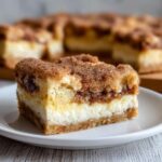 Close-up of a rich slice of sopapilla cheesecake showing layers of crust, cream cheese, and cinnamon topping.