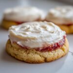 A close-up of one of the amazing strawberry cheesecake cookies, topped with strawberry jam and thick cream cheese frosting.
