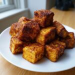 A pile of perfectly seasoned and crispy air fryer tofu crispy without cornstarch cubes on a white plate.