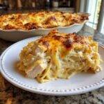 A generous serving of cheesy chicken spaghetti bake with a golden, bubbly cheese crust on a white plate.