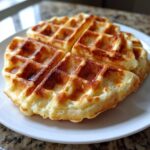 Close-up of fluffy, golden brown cottage cheese waffles served on a white plate.