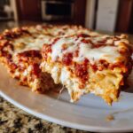 A close-up shot of a serving being lifted from a crockpot ravioli lasagna, showing melted cheese and layers.