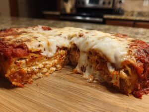 A cross-section of cheesy crockpot ravioli lasagna showing layers of pasta, ricotta, and sauce, with melted mozzarella stretching.
