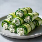 Close-up of stacked cucumber cottage cheese wraps filled with creamy herbed cottage cheese, garnished with dill.