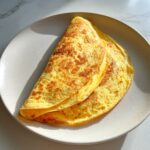 A golden-brown, folded egg wrap, representing the cottage cheese wrap, served on a light gray plate.