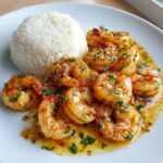 Close-up of delicious hawaiian garlic shrimp and rice served on a white plate.