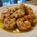 Close-up of succulent Hawaiian garlic shrimp scampi coated in garlic butter and parsley, served on a white plate.