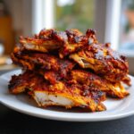 Close-up of a pile of freshly sliced, richly spiced homemade chicken doner kebab meat on a white plate.